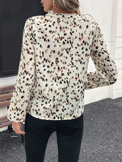 pikywiky long sleeve V-neck blouse featuring a cream base with a multi-colored abstract print, worn from the back.