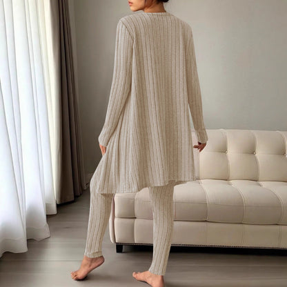 A woman wearing a pikywiky three-piece beige ribbed lounge set including a long cardigan and leggings, back view.