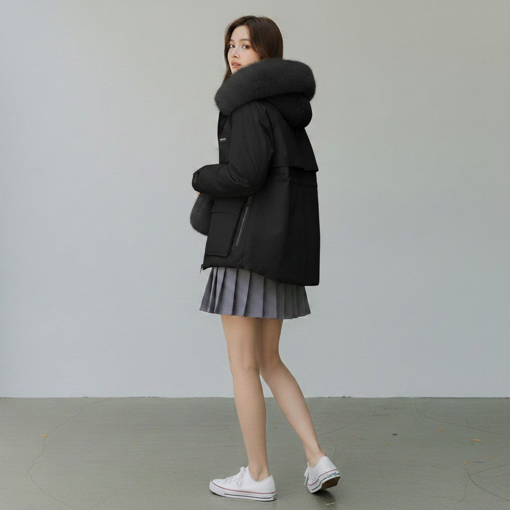 pikywiky black puffer jacket with a plush faux fur hood, worn by a woman with a grey pleated skirt and white sneakers
