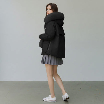 pikywiky black puffer jacket with a plush faux fur hood, worn by a woman with a grey pleated skirt and white sneakers