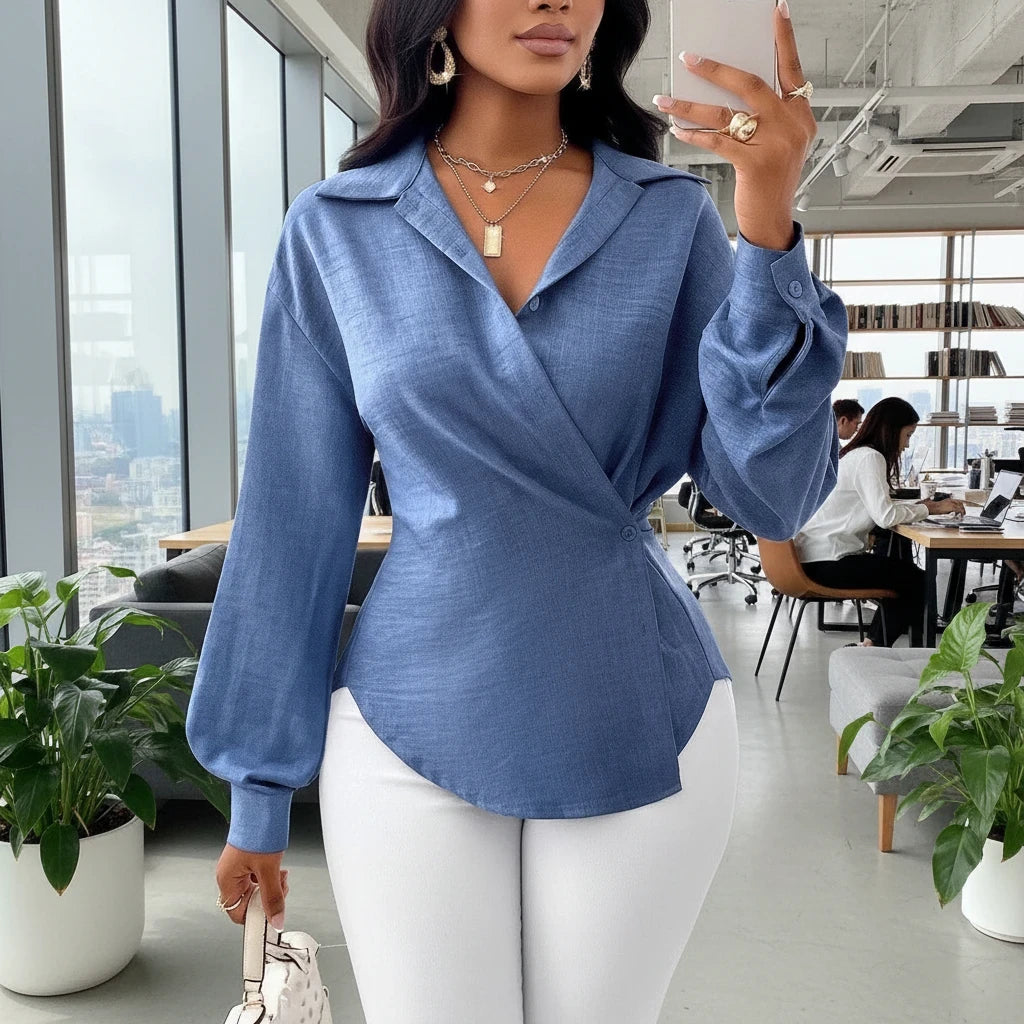 pikywiky muted blue long sleeve wrap blouse with collar and button cuffs worn with white trousers in an office