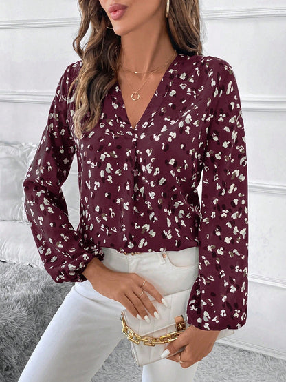 pikywiky burgundy long sleeve V-neck blouse with abstract print worn with white trousers and a gold chain handbag