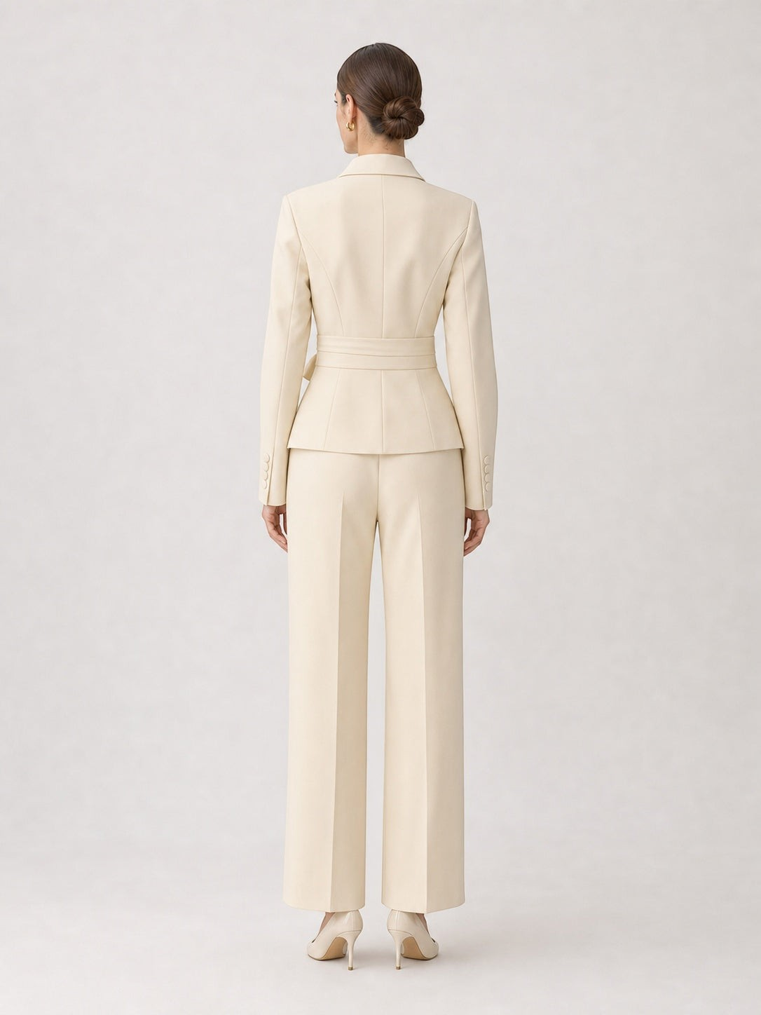 Back view of pikywiky cream tailored blazer and wide-leg trouser suit set with a belted waist on a model.