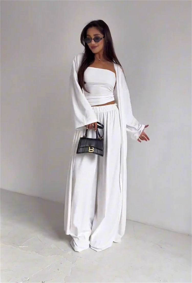 A woman wearing a pikywiky white three-piece lounge set with a tube top, wide-leg pants, and a long-sleeved cardigan.